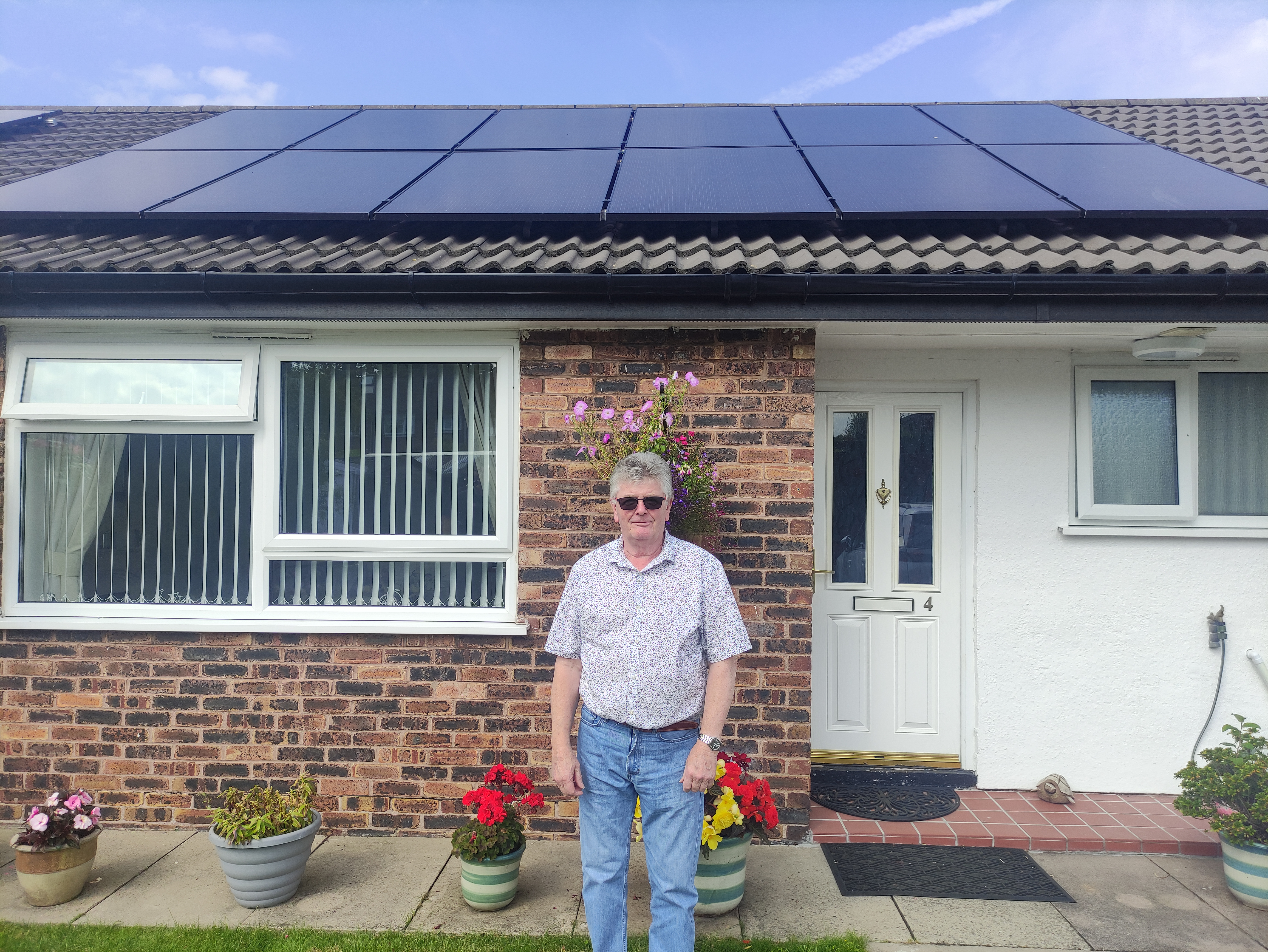 Our customer standing in front of his home, which has solar panels on the roof.
