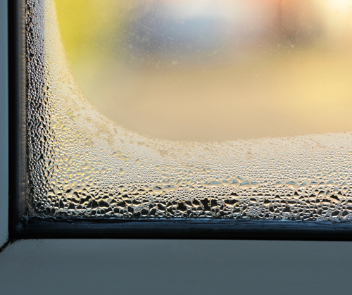 Droplets of water make the corner of a window appear foggy.